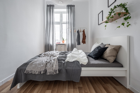 New bedroom with simple bed, clothes rack and wall shelfの写真素材