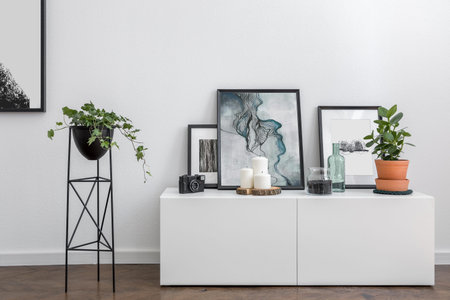 Home interior with white sideboard, metal flower stand and modern framed prints
