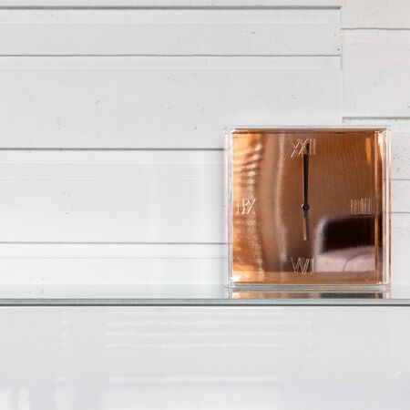 Modern golden glass clock standing on a white stylish dresserの写真素材