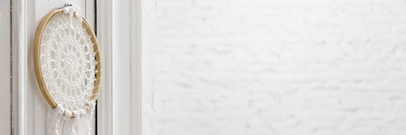 Panorama of white interior with knitted decoration hanging on wooden door