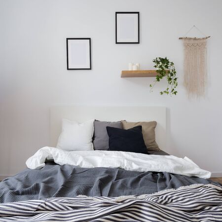 Simple bedroom in gray and white with double bed, and wall decorationの写真素材