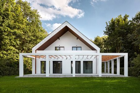 Exterior view of amazing designed house with wooden elements surrounded with green trees and lawnの写真素材