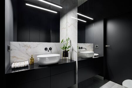 Elegant black bathroom with mirror wall and decorative marble tilesの写真素材