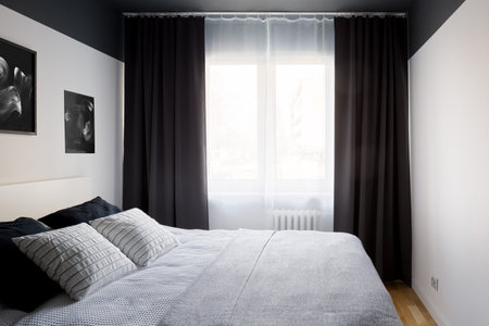 Stylish bedroom with big window with curtains and comfortable bed
