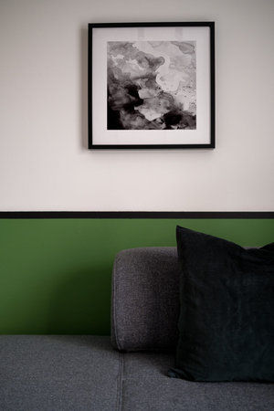 Close-up on gray sofa with pillows and white and green wall in the background