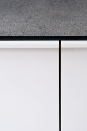 Close-up on kitchen white cupboard door and gray countertop