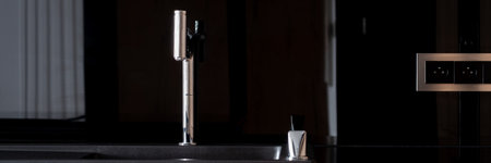 Panoramic close-up on modern black kitchen sink and new silver faucet, with mirrored black wall and...