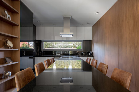 Elegant long dining table for eight in stylish kitchen with wooden walls