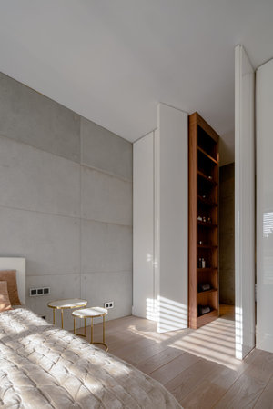 Bedroom with concrete wall with bathroom behind white doors high to the ceilingの写真素材