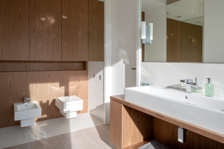 Bathroom with long washbasin, wooden furniture and square toilet and bidet