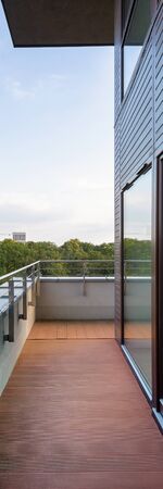 Vertical panorama of balcony with wooden floor in building with big windowsの写真素材