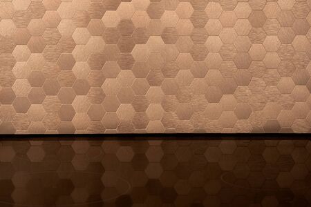 Close-up on elegant golden, hexagonal wall tiles and black induction hob with mirrored surfaceの写真素材