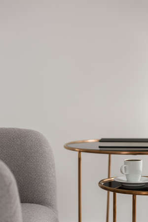 Close-up on modern gray armchair and two elegant, golden coffee tablesの写真素材