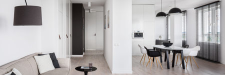 Panorama of white and black modern apartment with living room open to kitchen and corridor