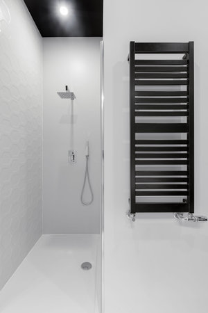 Modern bathroom in gray and black with stylish shower and new radiator