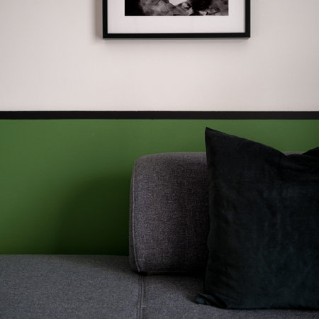 Close-up on gray sofa with pillows and white and green wall in the background