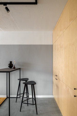 Modern and simple black table with two bar stools in kitchen with birch veneer on cupboards and...