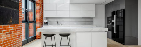 Panorama of stylish kitchen in loft apartment with white furniture, red brick on the walls and big...