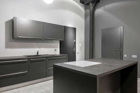Simple kitchen interior with stylish gray cupboards, countertops and drawers and white and gray wallsの写真素材