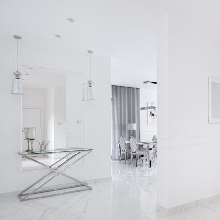 Luxury white corridor with marble floor, mirror with silver and glass console table and view to dining room in elegant villaの写真素材