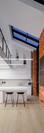 Vertical panorama of white kitchen in loft apartment with mezzanine floor, brick walls and big windowsの写真素材