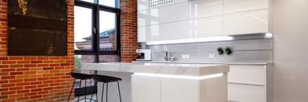 Panorama of luxury white kitchen interior with loft style brick wall and big windowの写真素材