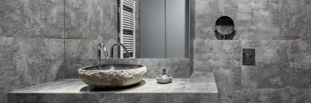 Panorama of fancy stone style washbasin in dark bathroom with gray wall tilesの写真素材