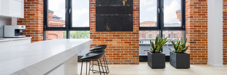Panorama of modern kitchen with white furniture, marble countertop, amazing big windows and stylish red brick on the wallsの写真素材