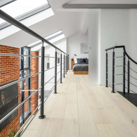 Bright corridor on second floor in loft apartment, with railing, brick wall, big windows and bedroom at the endの写真素材