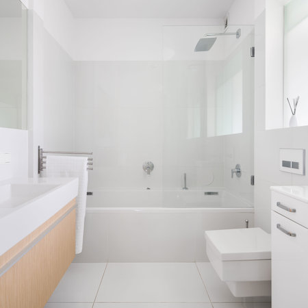 Spacious and bright bathroom with gray tiles on walls and floor and big bathtub with shower and...