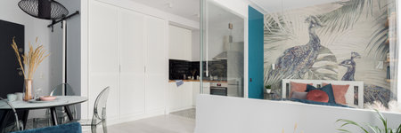 Panorama of small and stylish designed studio apartment with dining area open to kitchen and with eclectic bedroom behind glass wallの写真素材