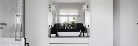 Panorama of stylish black and white bathroom with two wardrobes, white cabinet under modern washbasin with big mirrorの写真素材