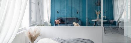Panoramic view from bedroom with glass wall to elegant living room with dining tableの写真素材