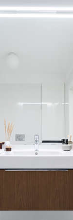 Vertical panorama of stylish bathroom with big mirror above elegant washbasin with wooden drawerの写真素材