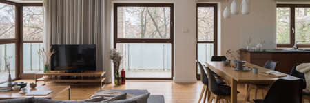 Panorama of stylish, spacious and bright apartment with living room, dining room and kitchen in one room with amazing big windowsの写真素材