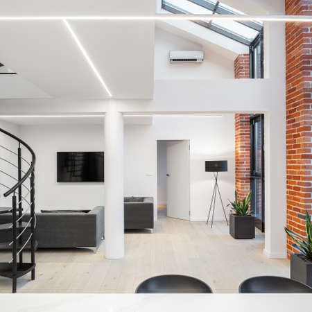 Modern and spacious loft apartment in white with big windows, brick walls and ceiling lightの写真素材