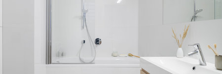 Panorama of stylish bathroom in classic white wall tiles, white washbasin and with simple bathtub...