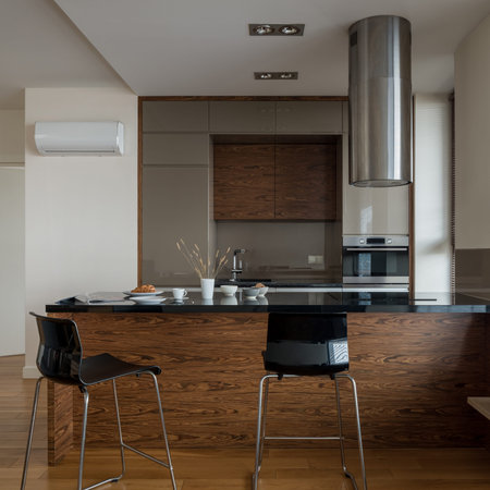 Dark and spacious kitchen with big kitchen island with black countertop and two black chairs