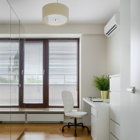 Bright and small home office room with white furniture, mirrors on wardrobe doors and big windowの写真素材
