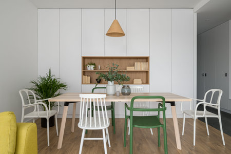 Simple and nice dining room with long wooden table, different and stylish, white and green chairs