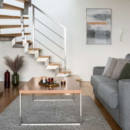 Close-up on simple, wooden coffee table with decorations in living room comfortable sofa and with stairs to second floorの写真素材
