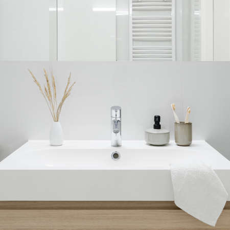 Close-up on classic and white bathroom washbasin with decorations under mirrorの写真素材