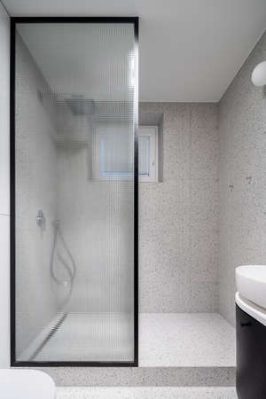 Modern bathroom with terrazzo style tiles and shower behind stylish reinforced glassの写真素材