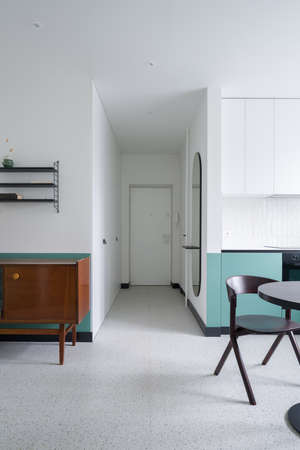 View from stylish and bright kitchen with dining table to corridor with white doors in modern apartment with terrazzo floorの写真素材
