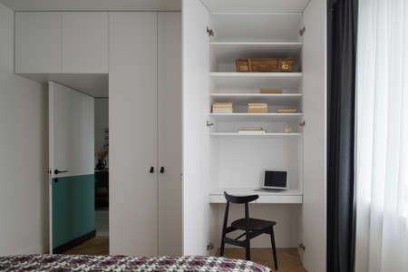 Functional idea with small desk to work in white wardrobe in spacious bedroomの写真素材