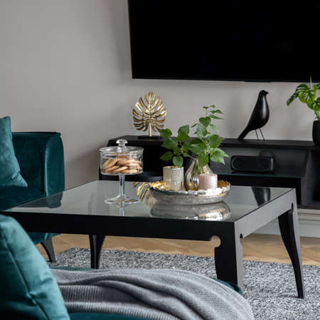 Close-up on nice decorations, vase, candle and cookie container on square coffee table with glass countertopの写真素材