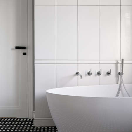 White bathroom with luxurious freestanding bathtub with silver wall mounted tapsの写真素材
