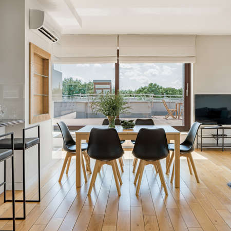 Spacious dining room with wooden table and black chairs and many window doors to big terraceの写真素材