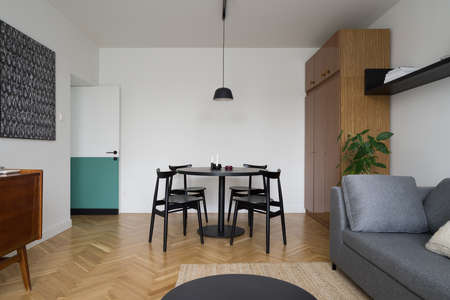 Eclectic style living room with modern dining area and couch, new pendant lamp, vintage, wooden wardrobe and wooden floorの写真素材