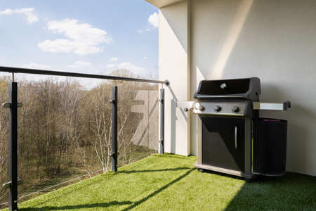 Spacious terrace with modern glass balustrade, synthetic grass and new gas grillの写真素材